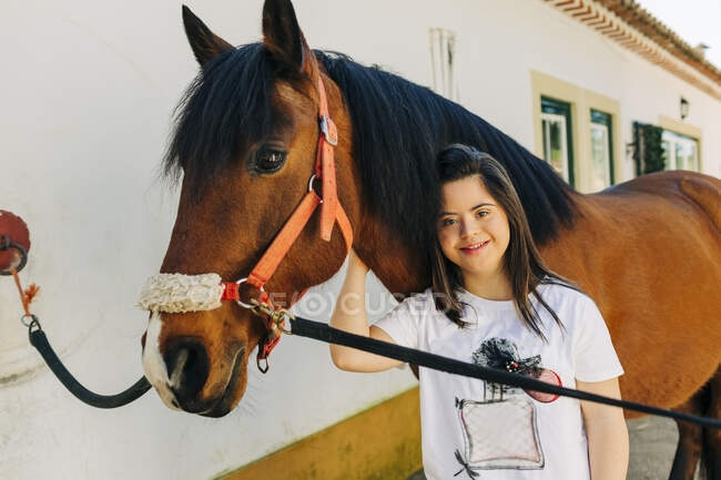 Teenager with down syndrome taking care of horse and preparing horse to ride — Stock Photo