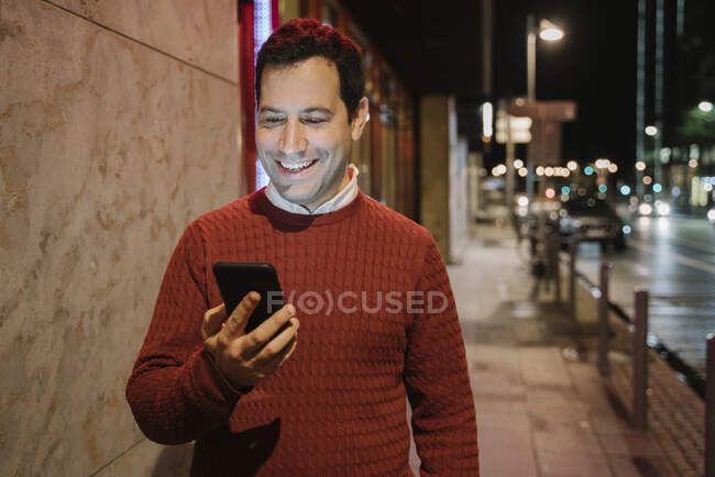 Портрет щасливого інспектора в місті, який дивиться на мобільний телефон, відвертий фурт, зародок — стокове фото