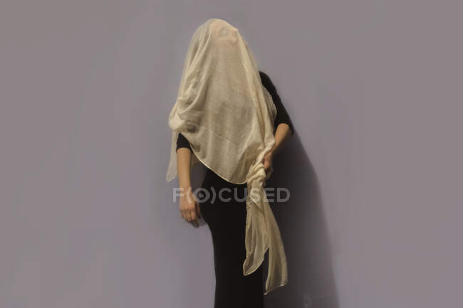 Femme sous le tissu devant le mur gris — Photo de stock