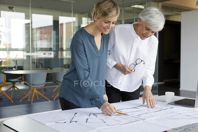 Zwei Geschäftsfrauen arbeiten gemeinsam an Bauplan im Büro — Stockfoto