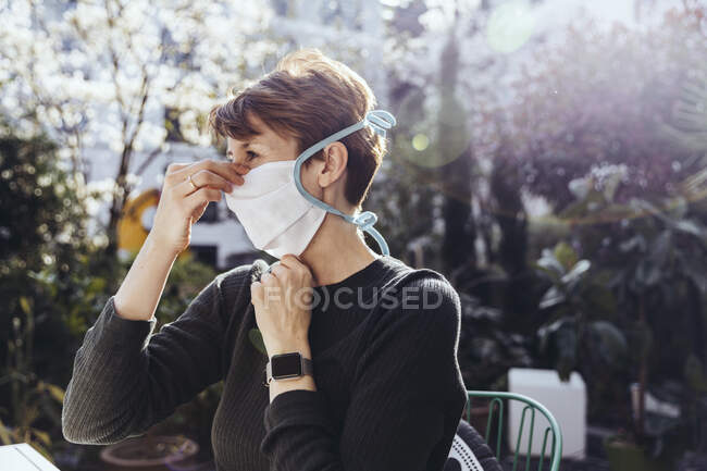 Femme assise dans le jardin, portant un masque facial — Photo de stock