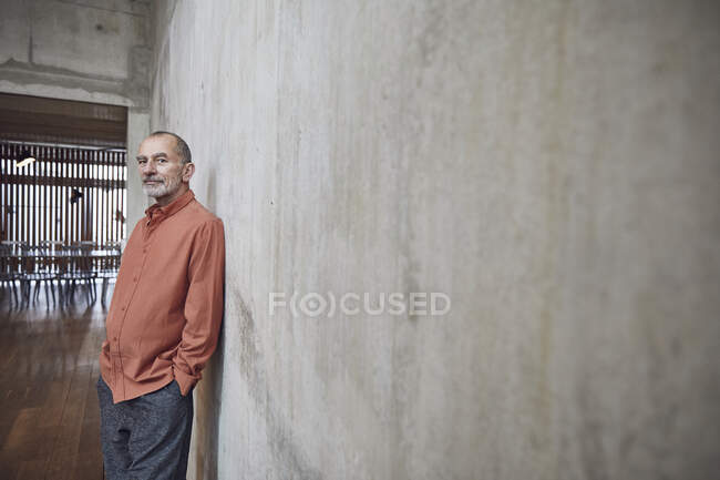 Uomo d'affari creativo appoggiato al muro nel suo ufficio minimalista — Foto stock