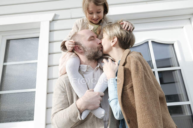 Счастливая семья обнимается и целуется перед своим домом — стоковое фото