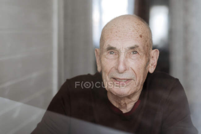 Ritratto di vecchio sorridente che guarda fuori dalla finestra — Foto stock