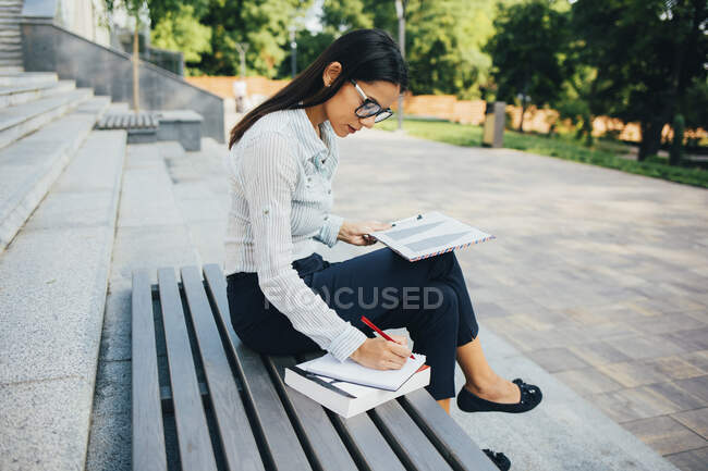 Donna d'affari con appunti seduta su una panchina in un parco — Foto stock