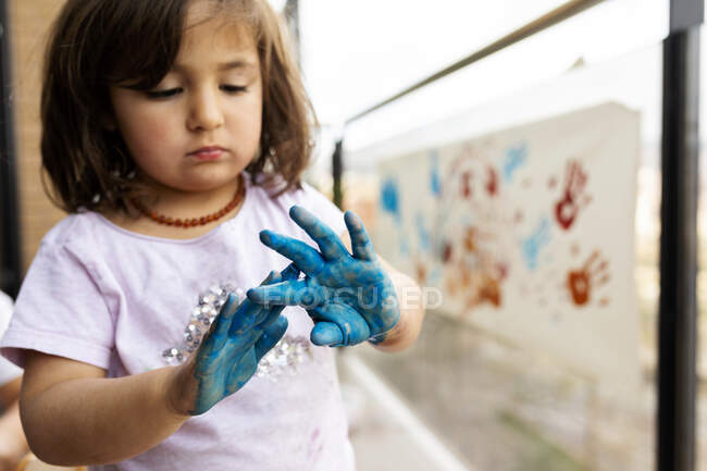 Маленька дівчинка бавиться розфарбованими руками. — стокове фото