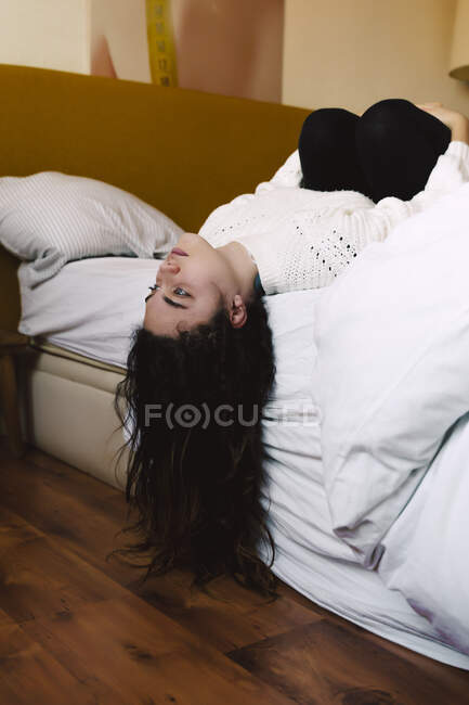 Портрет задумливої дівчини лежачої на ліжку, дивлячись на відстань — стокове фото