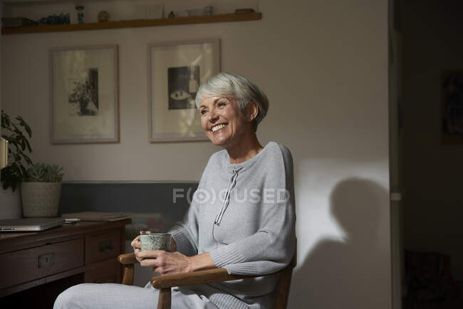 Портрет счастливой пожилой женщины, отдыхающей с чашкой чая дома — стоковое фото
