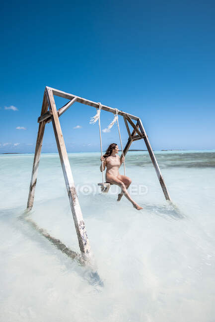 Женщина качается на качелях в море, на Багамах, на Карибах — стоковое фото