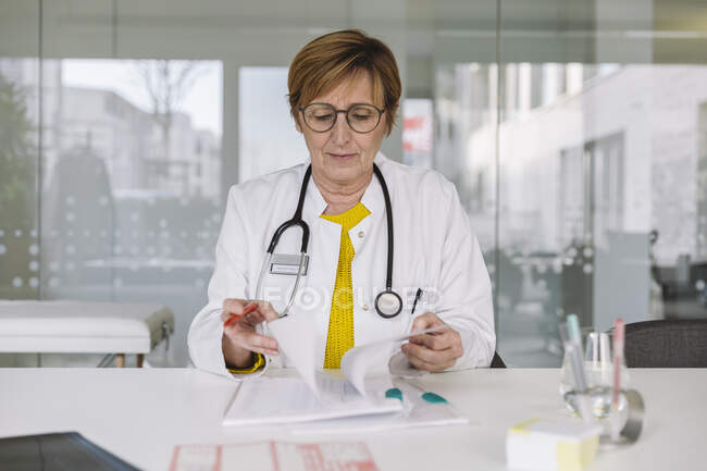 Doctor sitting at desk reviewing documents — Stock Photo