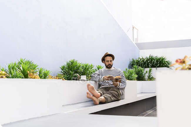 Человек, сидящий на балконе и читающий книгу — стоковое фото
