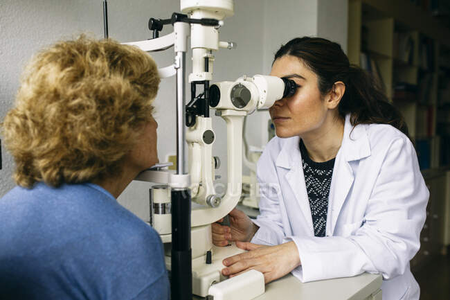 Oftalmólogo examinando la vista de un paciente mayor - foto de stock