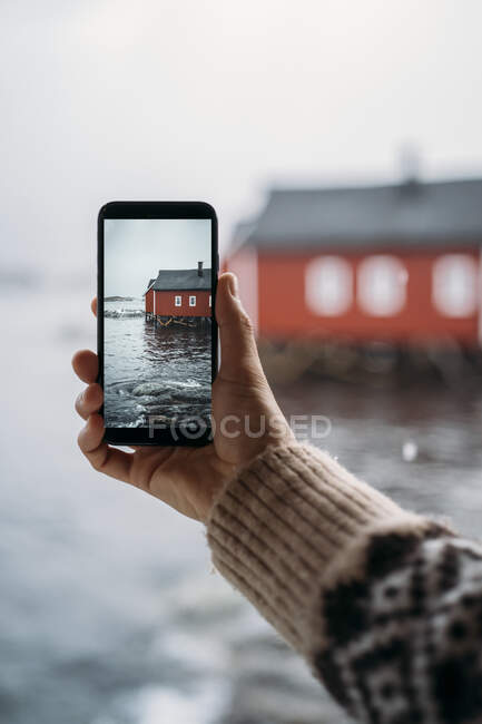 Gros plan d'un touriste prenant une photo de téléphone portable d'une cabane sur la côte, Lofoten, Norvège — Photo de stock