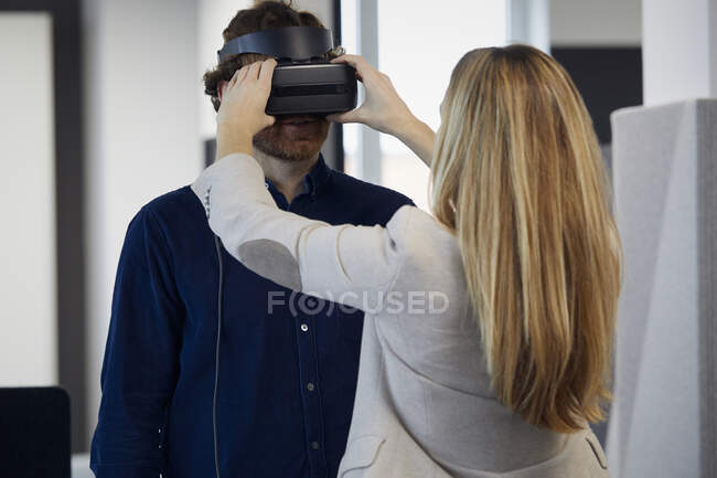 Businesswoman applying VR glasses on businessman in office — Stock Photo
