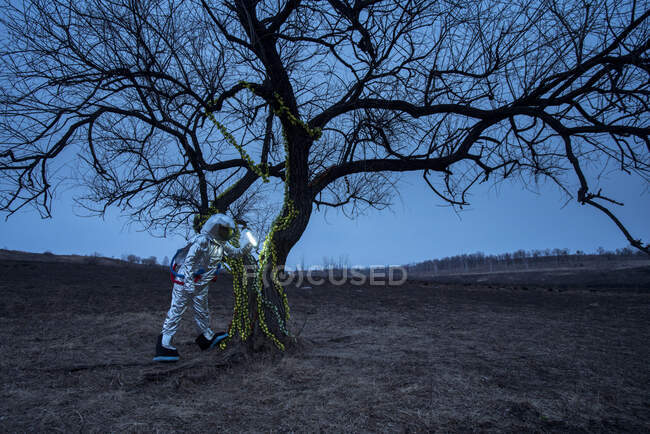 Spacewoman descubriendo un árbol por la noche - foto de stock