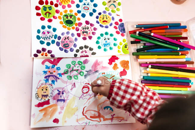 Маленька дівчинка малює потворні віруси з маркерами кольорів вдома. — стокове фото