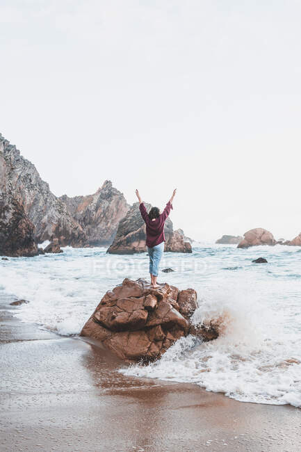Jovem mulher de pé sobre pedra na Praia da Ursa, Lisboa, Portugal — Fotografia de Stock