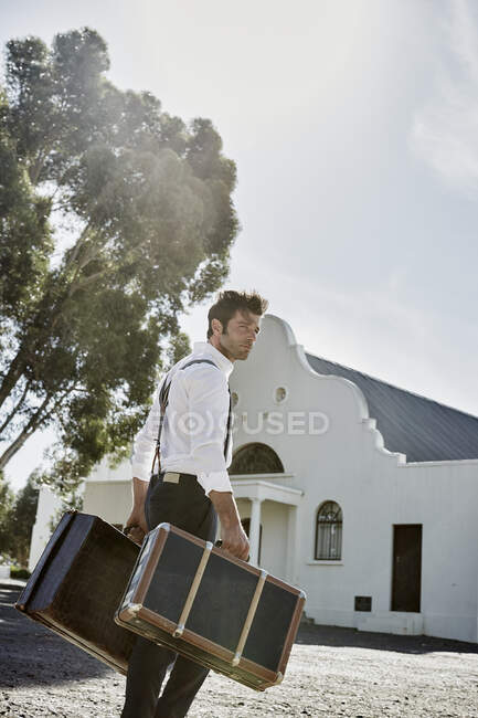 Uomo in abiti vecchio stile con valigie in campagna — Foto stock