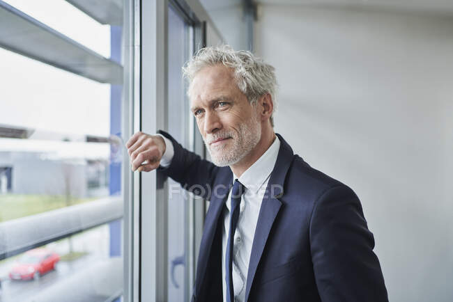 Retrato de empresario confiado mirando por la ventana - foto de stock