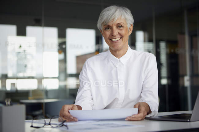 Portrait of content senior businesswoman at desk in her office — Stock Photo
