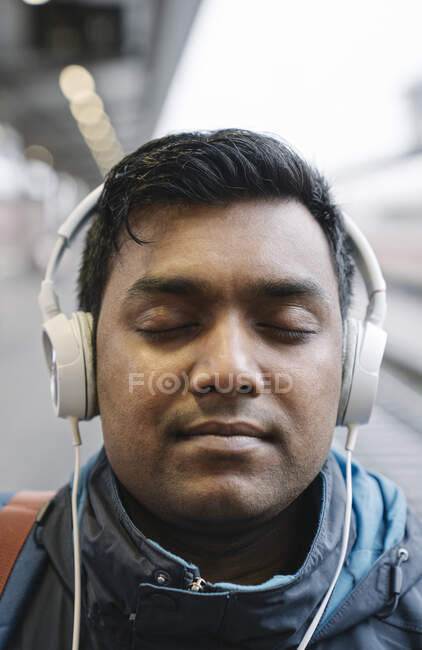 Портрет мужчины с закрытыми глазами в наушниках на вокзале — стоковое фото