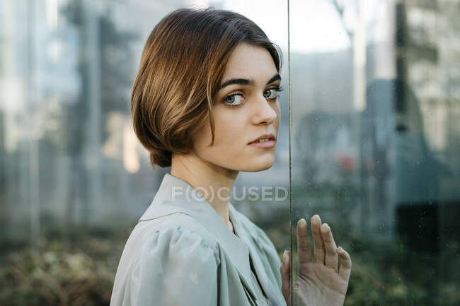 Portrait of woman with her face resting on a glass pane — Stock Photo
