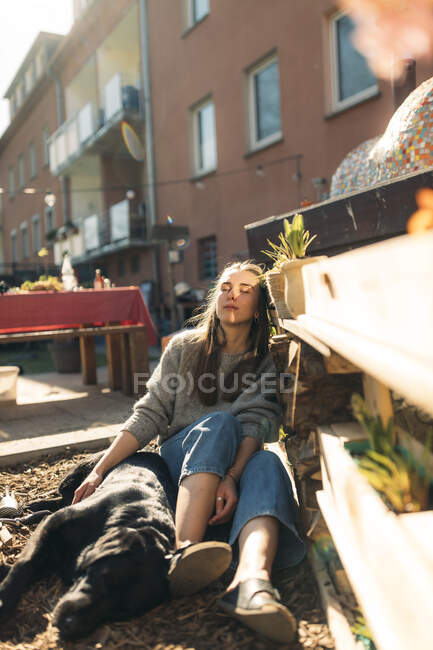 Relaxed young woman with dog in garden — Stock Photo