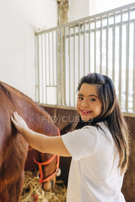 Teenager with down syndrome taking care of horse and preparing horse to ride — Stock Photo