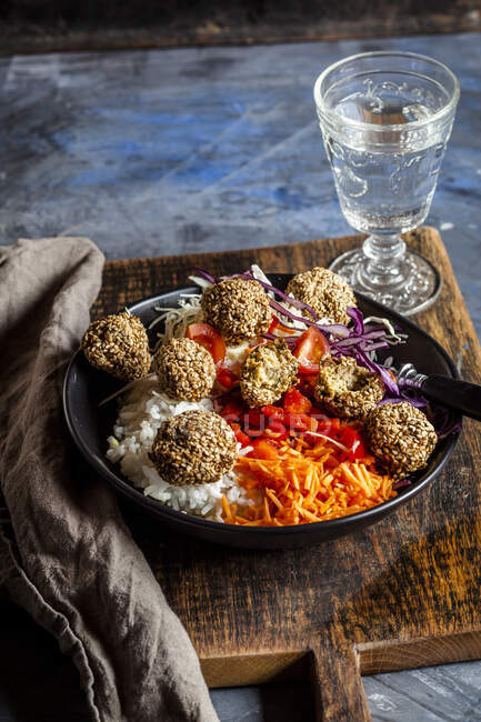 Bowl of ready-to-eat salad with white and red cabbage, carrots, rice and spinach falafel — Stock Photo