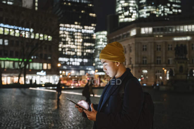 Чоловік використовує планшет у місті вночі — стокове фото