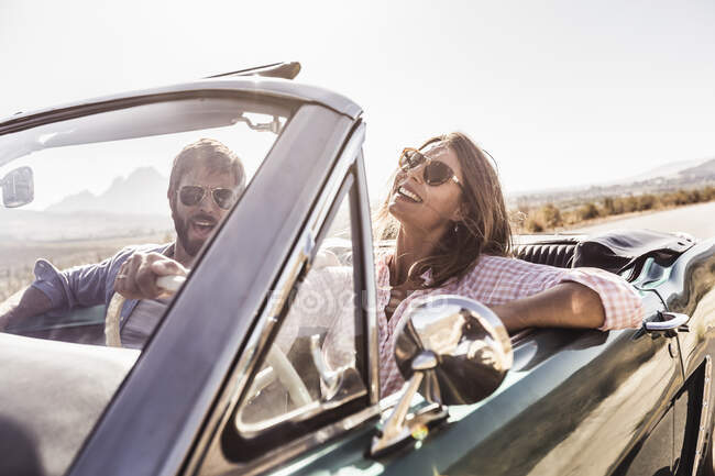 Happy couple in convertible car on a road trip — Stock Photo