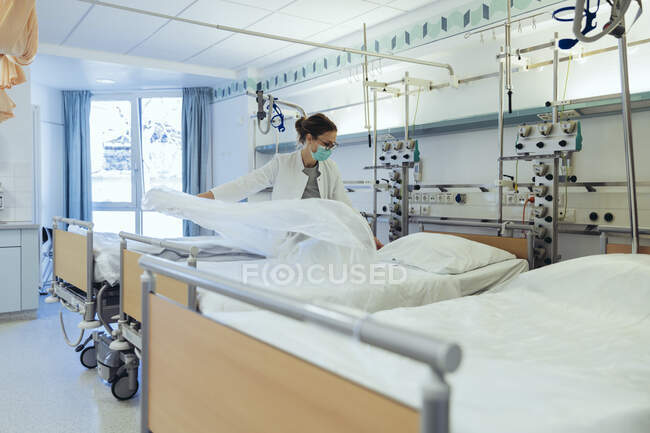 Doctor preparing bed in hospital room — Stock Photo