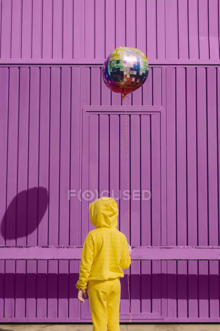 Vista posteriore dei bambini vestiti di palloncino giallo davanti allo sfondo viola — Foto stock