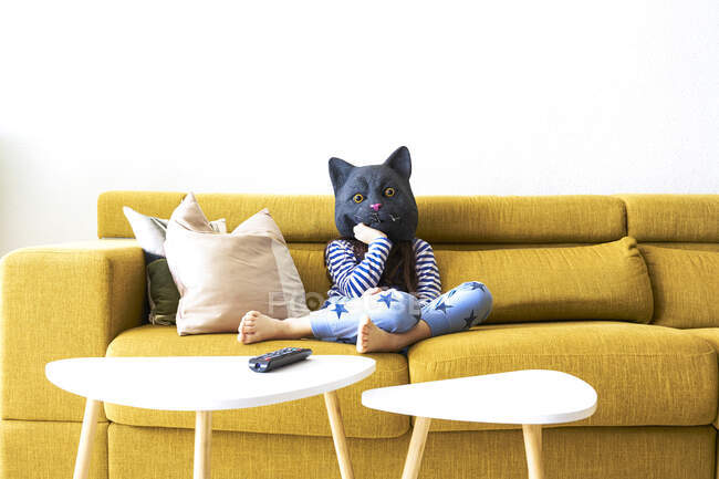 Скучающая девушка сидит на диване в маске кота — стоковое фото
