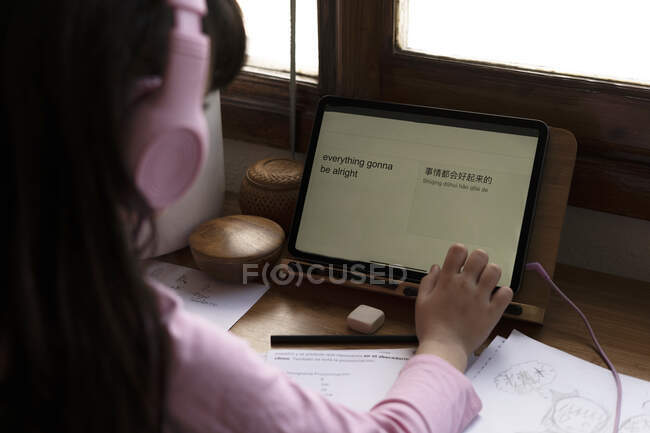 Mädchen übersetzt Englisch auf Chinesisch auf digitalem Tablet am Schreibtisch im Haus — Stockfoto