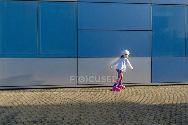 Маленькая девочка в защитном шлеме, катающаяся на коньках при солнечном свете — стоковое фото