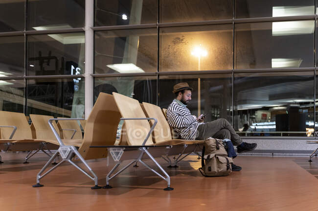 Homme assis dans la zone de départ de l'aéroport en utilisant un téléphone intelligent — Photo de stock