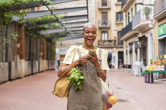 Laughing wman with grocery bag and cell phone in the city — Stock Photo