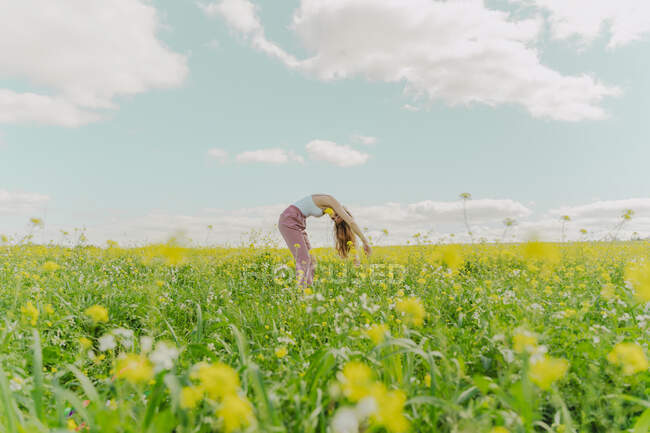 Young woman bending over in a flower meadow in spring — Stock Photo