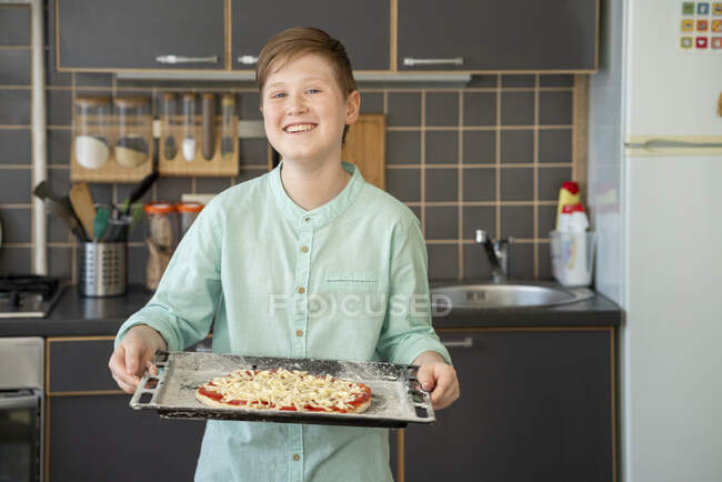 Porträt eines stolzen Jungen mit Backblech und roher hausgemachter Pizza — Stockfoto
