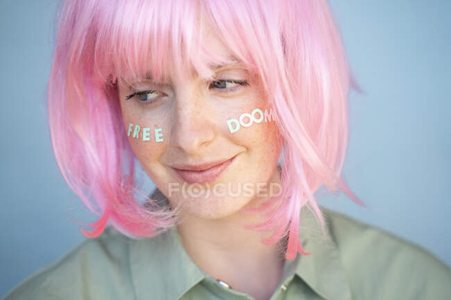 Giovane donna con parrucca rosa, lettere sul viso, destino libero — Foto stock