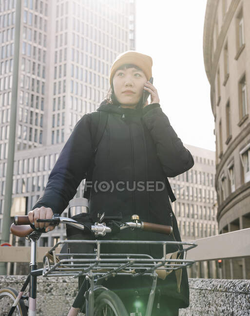 Woman with bicycle on the phone in the city, Frankfurt, Germany — Stock Photo
