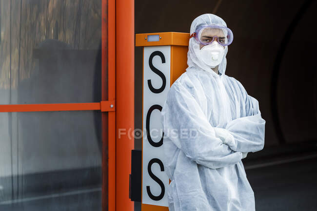 Retrato del hombre vestido con ropa protectora apoyado en el teléfono SOS - foto de stock