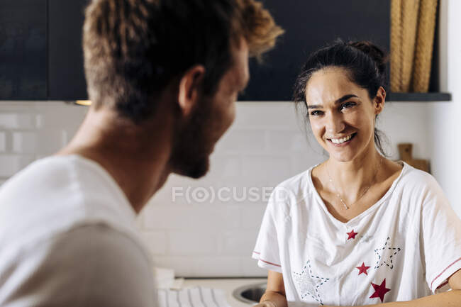 Retrato de mulher jovem sorrindo para o namorado na cozinha — Fotografia de Stock