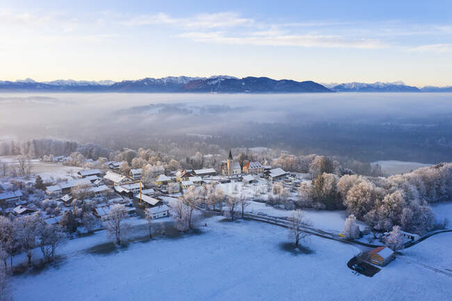 Germania, Baviera, Hechenberg, Drone vista del villaggio di campagna innevato all'alba nebbiosa — Foto stock
