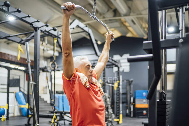 Senior man practising at cable machine in gym — Stock Photo