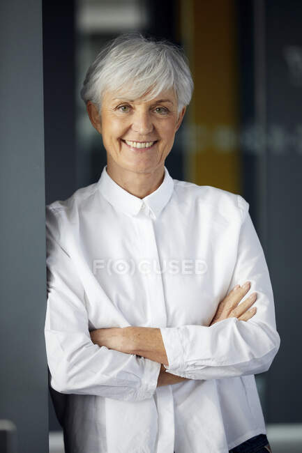Portrait of smiling senior businesswoman with arms crossed — Stock Photo