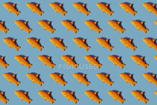 Modèle de poisson en plastique jaune sur fond bleu — Photo de stock