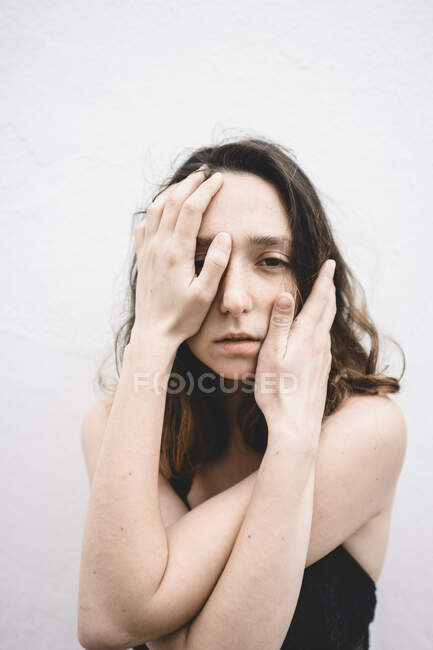 Retrato de una joven deprimida con las manos en la cara - foto de stock