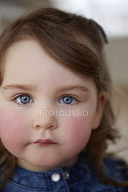 Retrato de niña con ojos azules y mejillas rojas - foto de stock